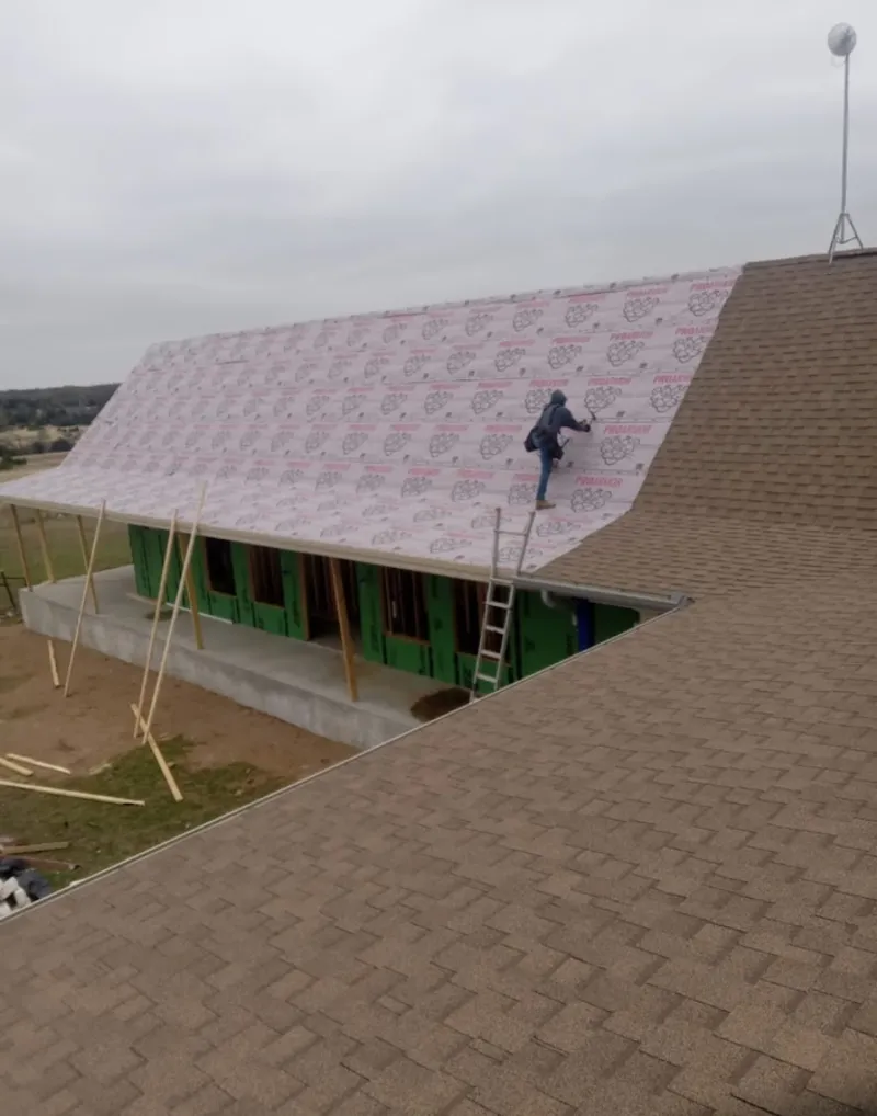 Worker preparing underlayment for a metal roof installation in Minnetonka
